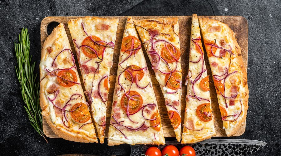 Homemade Flammkuchen or tarte flambee with cream cheese, bacon, tomato and onions.