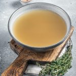 Bone meat chicken broth in a plate. Gray background. Top view