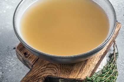 Bone meat chicken broth in a plate. Gray background. Top view