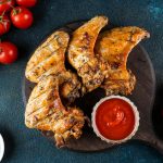 Grilled spicy chicken wings with ketchup . Top view with copy space. BBQ concept.