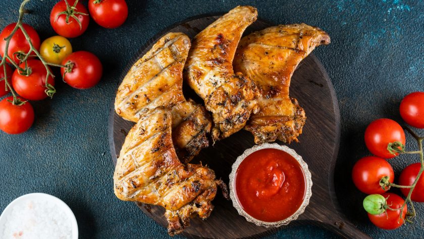 Grilled spicy chicken wings with ketchup . Top view with copy space. BBQ concept.