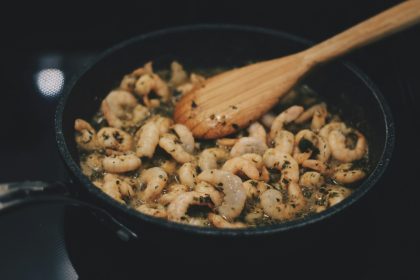 Shrimps in herb sauce sautéing in a pan on a stovetop