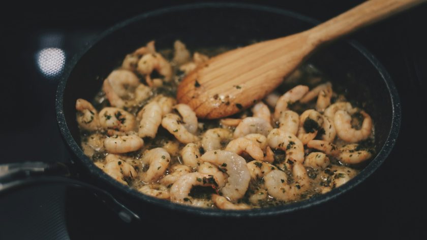 Shrimps in herb sauce sautéing in a pan on a stovetop