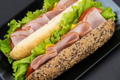Tasty sandwiches with ham on dark background