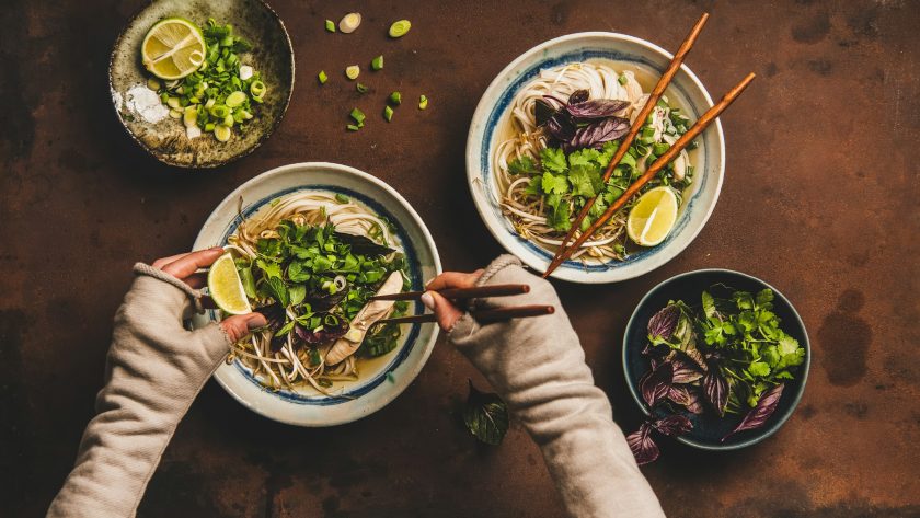 Womans hands with chopsticks and lime over vietnamese soup Pho-Ga